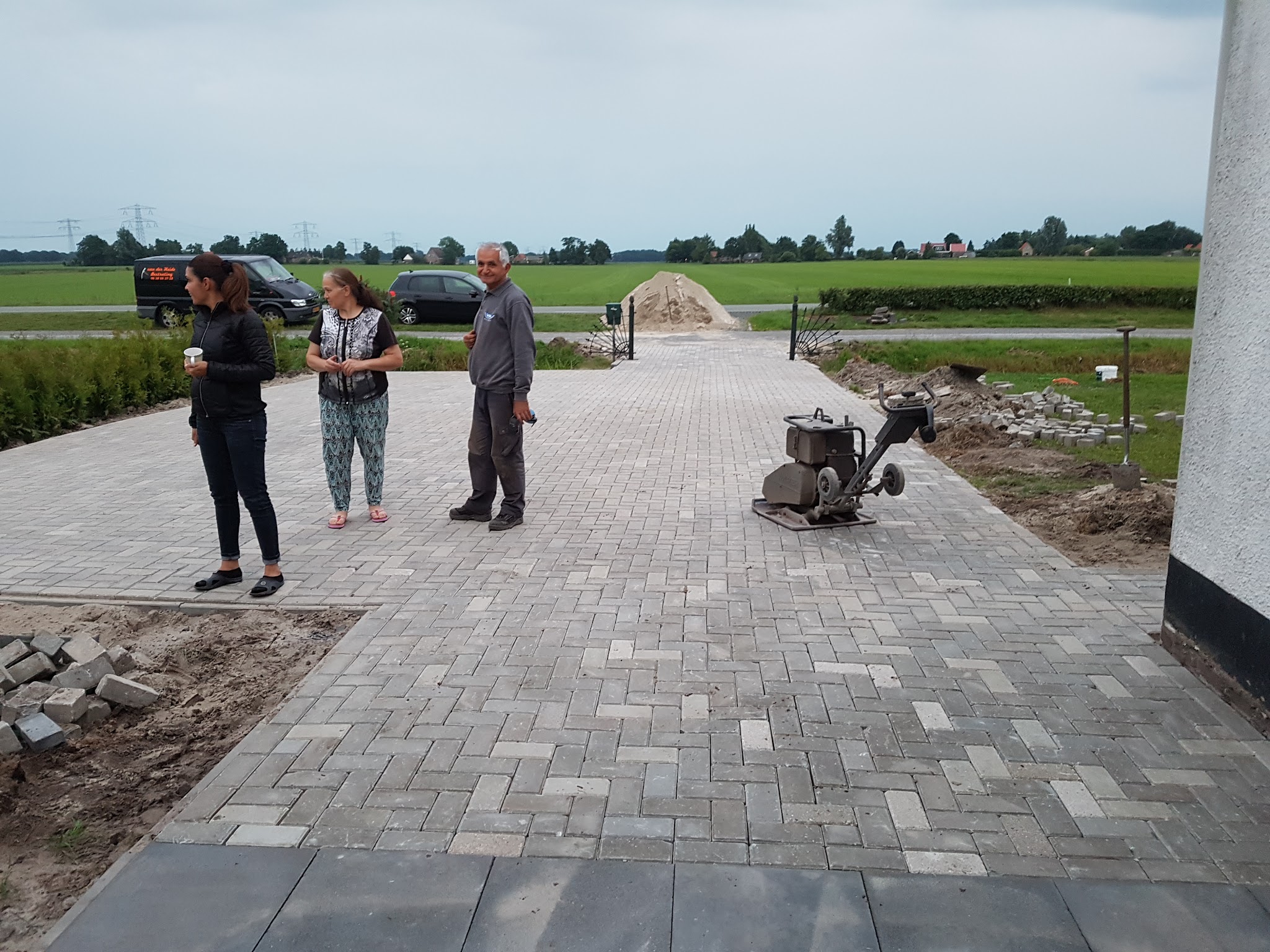 Grote oprit in visgraatverband, bijna klaar, met een trilplaat erop en weiland op de achtergrond